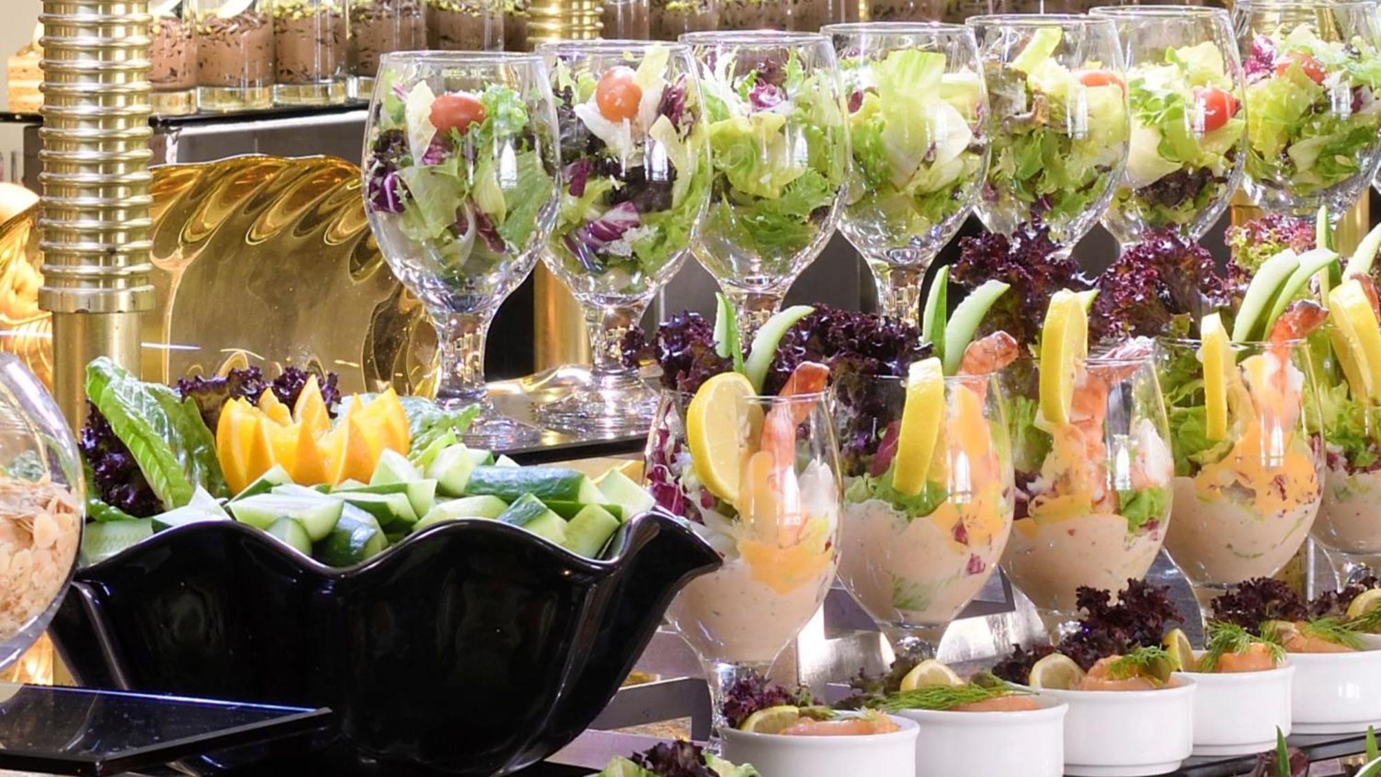 Intercontinental Dar Al Iman Madinah By Ihg Hotel Медина Екстериор снимка The photo features an elegant display of food items. In the background, there are several clear glasses filled with vibrant salads, featuring various types of greens and garnishes. In the foreground, there is a decorative black bowl containing cut pi