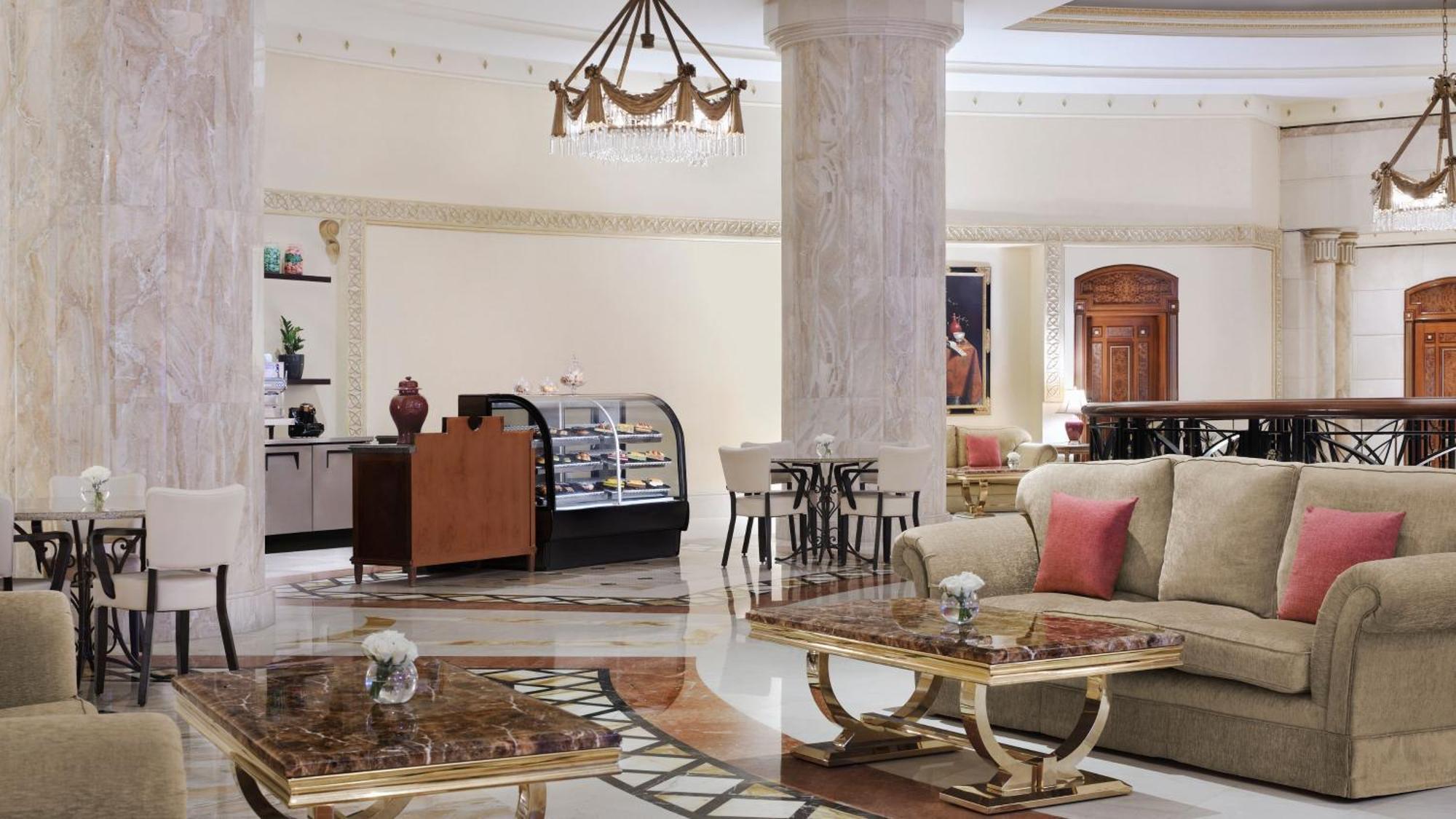 Intercontinental Dar Al Iman Madinah By Ihg Hotel Медина Екстериор снимка The photo shows a luxurious hotel lobby or lounge area. It features elegant marble floors and tall columns. There are comfortable seating arrangements with a sofa and stylish tables that have marble tops. A display case for pastries or refreshments i