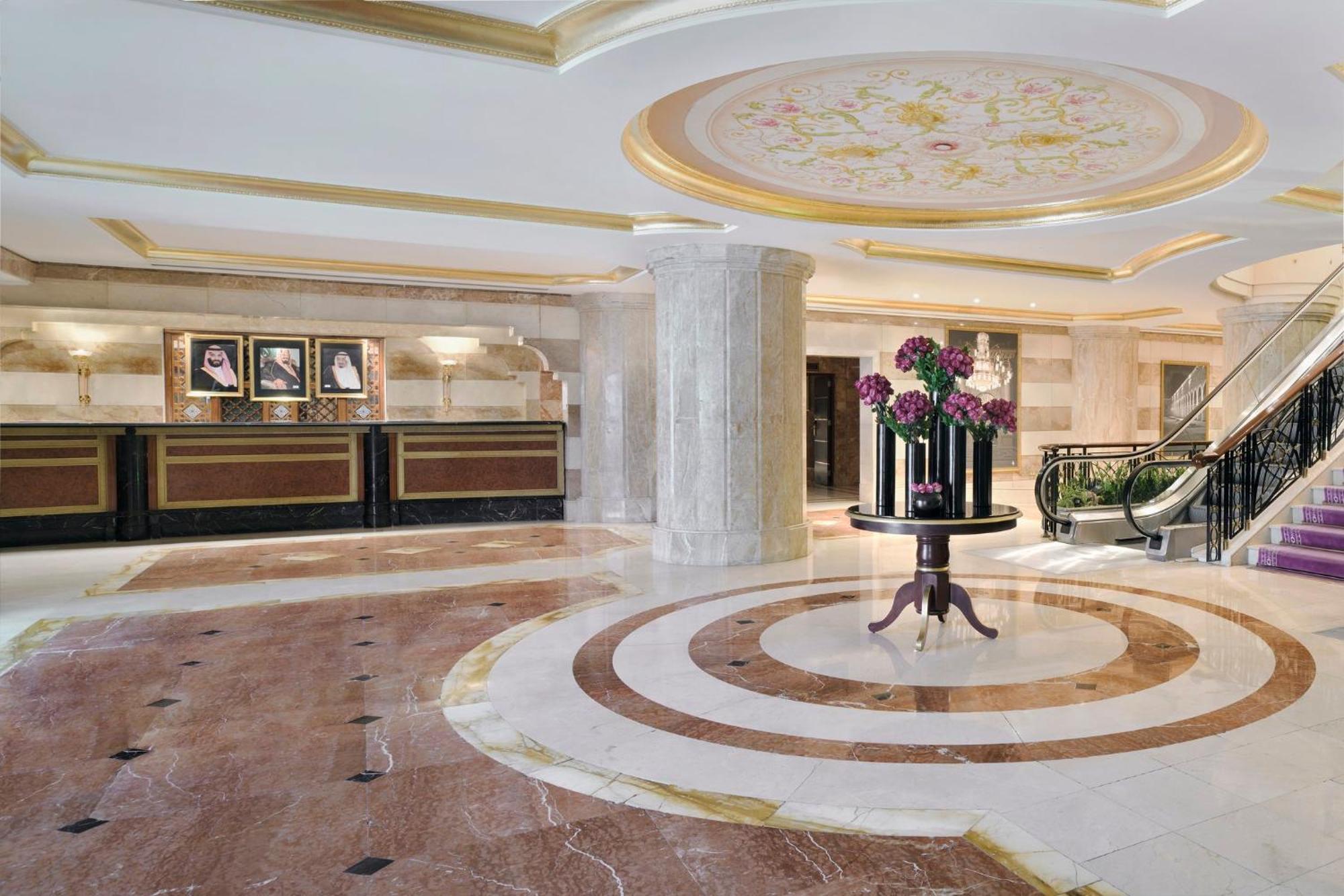 Intercontinental Dar Al Iman Madinah By Ihg Hotel Медина Екстериор снимка The photo shows a luxurious hotel lobby. The space features elegant marble flooring with circular designs, complemented by a large, decorative ceiling. In the center, there is a round table adorned with a floral arrangement. Behind the table, a recep