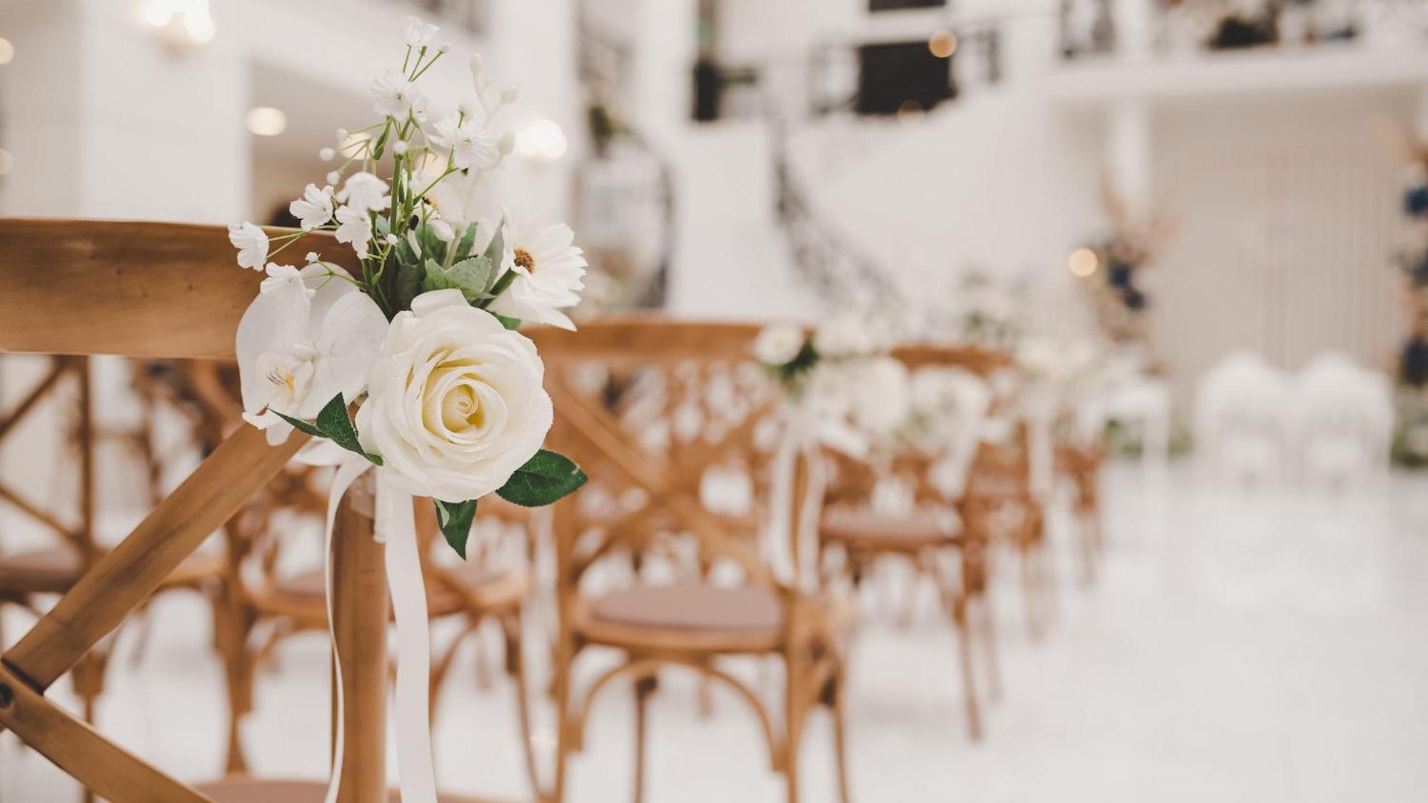 Intercontinental Dar Al Iman Madinah By Ihg Hotel Медина Екстериор снимка The photo showcases a beautifully arranged event space, likely set up for a wedding or special occasion. In the foreground, wooden chairs are neatly lined up, some adorned with decorative floral arrangements. The flowers include white roses and small
