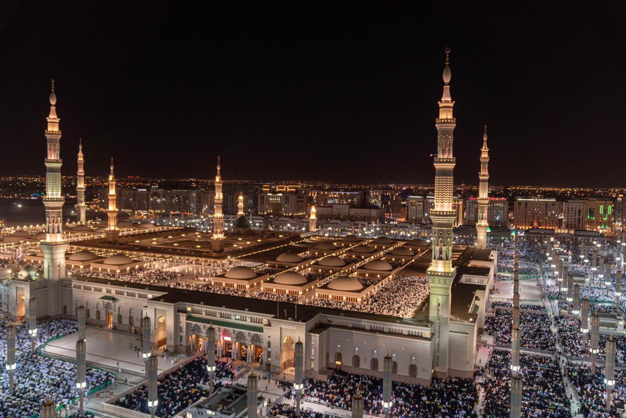Intercontinental Dar Al Iman Madinah By Ihg Hotel Медина Екстериор снимка The photo shows a panoramic view of a large mosque complex illuminated at night. It features tall minarets with lights, a vast courtyard filled with people, and a beautifully lit architectural design. The overall ambiance suggests a significant space