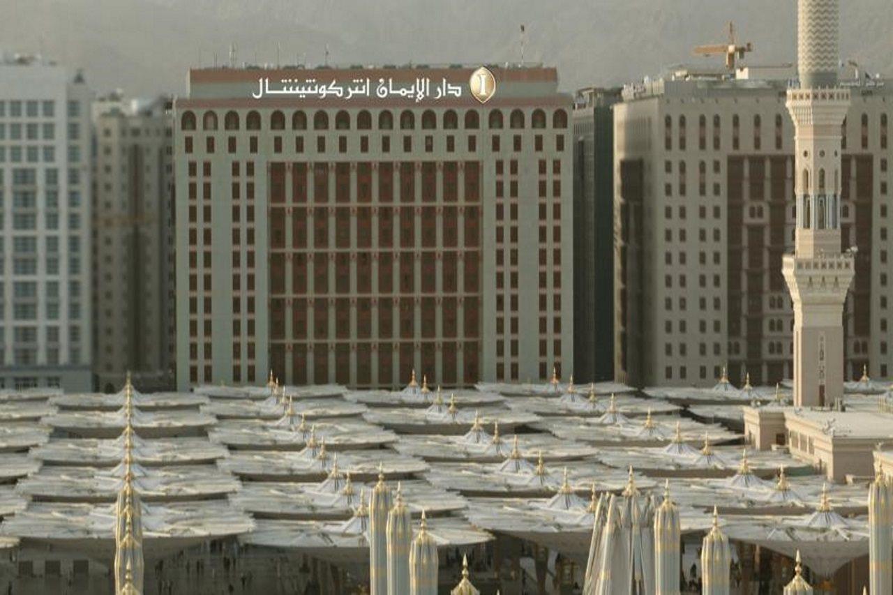 Intercontinental Dar Al Iman Madinah By Ihg Hotel Медина Екстериор снимка The photo shows a view of a large building with a modern architectural design, which appears to be a hotel or a commercial establishment. In front of the building, there are several large white canopies that provide shade, likely in a public space or