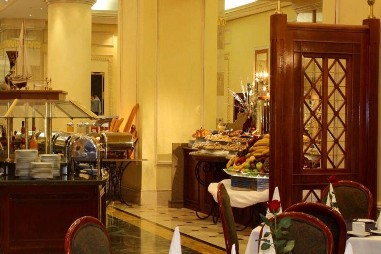 Intercontinental Dar Al Iman Madinah By Ihg Hotel Медина Екстериор снимка The photo shows an elegant dining area, likely within a restaurant or a hotel. There's a buffet setup on one side with various food items displayed, including pastries and fruits. The room features warm lighting, polished floors, and decorative walls